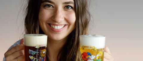 Frau im Dirndl lacht mit zwei Biergläsern in der Hand