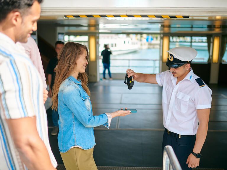 Eine Frau zeigt das Handyticket für eine Fahrt mit dem BSB Schiff kontaktlos dem Kontrolleur
