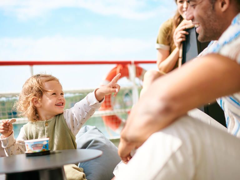 Ein Kind beim Eis essen mit dem Eltern im Hintergrund auf dem Schiff.