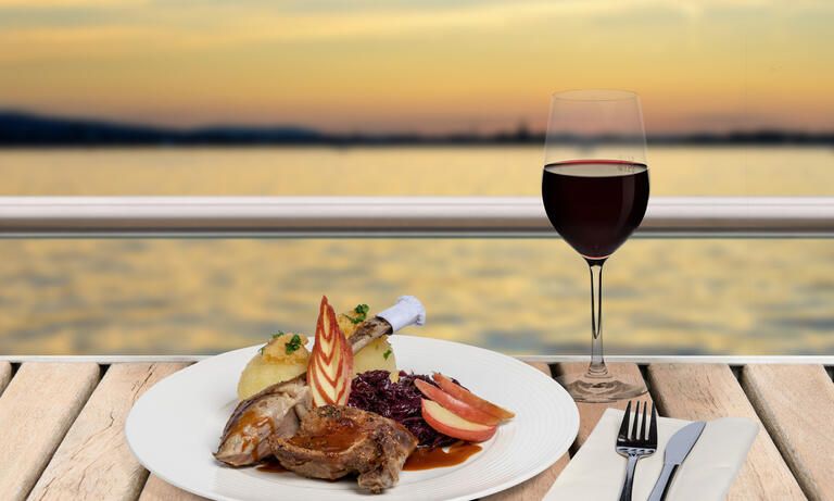 Teller mit leckeren Gans essen auf dem Schiff, dazu ein Rotwein mit Blick auf den Bodensee.