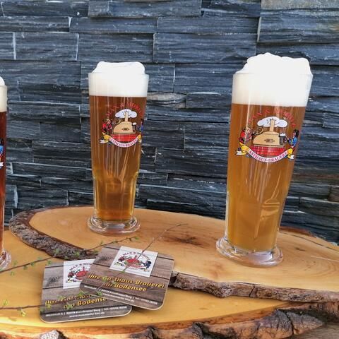Drei gefüllte Biergläser der Marke Max&Moritz auf einem Holzbrett